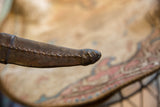 Hand-stitched seam and weathered surface detail on the tip of a handmade leather sheath.