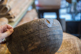 Hand-carved patterns and authentic aged cracks on the rim of a vintage wooden bowl.