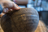 Hand showing the carved rim and aged character of a vintage wooden bowl.
