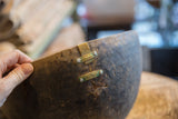 Vintage African wooden bowl, detail of a crack with brass-toned metal repairs.