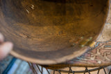 Aged African wooden bowl interior, highlighting deep brown patina, cracks, and metallic repairs.
