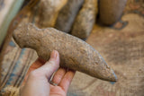 A hand holds the antique Neolithic stone weapon, illustrating its scale and rough-hewn texture.