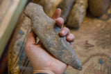 Primitive African stone weapon held to show its ergonomic shape and scale.