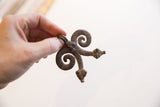 Hand holding the vintage double snake pendant to display its scale and etched texture.