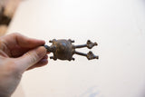 Vintage African turtle pendant with an aged patina held in hand for scale.