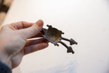 Underside view of the double-headed turtle pendant highlighting its hollow construction and aged metal patina.