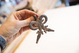 A hand holding the vintage African crocodile pendant to display its scale and aged texture.