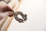 Vintage African double lizard pendant held to show its scale and aged metallic texture.