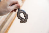 Vintage African double lizard pendant held in hand, showing its scale and weathered texture.