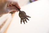 Hand-held view of the vintage African crocodile pendant highlighting its aged metal texture.
