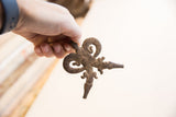 A hand holding the vintage double crocodile pendant, showing its scale and rustic texture.
