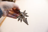 Vintage African snakes pendant held to show its scale and dark, textured patina.