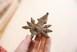 The sculptural form and textured metal of a vintage African snake pendant held in hand.