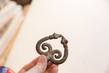 Hand holding the vintage double snake pendant, showing its scale and texture.