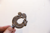 Vintage African chameleon pendant with a dark patina held in hand at an angle.