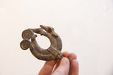 A hand holds the vintage African double chameleon pendant, showing its form and scale.