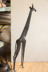 Profile view of the tall vintage African giraffe sculpture with its dark patina.