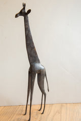 Full left-side view of the tall, slender vintage African giraffe sculpture.