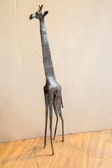 Stylized form of a vintage African giraffe sculpture with slender limbs and a dark patina.