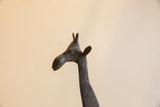 Close-up of the vintage African giraffe's sculpted head with its dark, textured patina.
