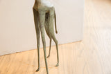 Side view of the vintage African giraffe sculpture's long, slender legs and tail.