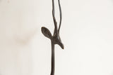 Profile of the vintage gazelle sculpture's head showing its carved ear and long horns.