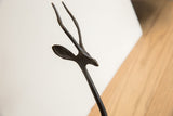 Textured details on the slender horns and stylized ear of the gazelle sculpture.