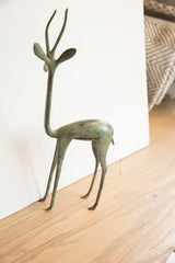 Vintage African gazelle sculpture with slender legs and aged green-brown patina.