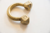 Faceted ends of an antique bronze Tuareg cuff with etched geometric patterns and a gold patina.