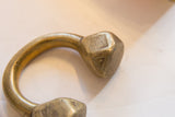 Etched markings and aged gold patina on the faceted end of the bronze cuff.