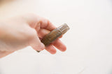 Hand holding an antique African cuff bracelet, highlighting its rich patina and etched details.
