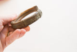 Antique bronze and copper alloy cuff bracelet held in hand for scale.