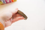 Antique African cuff bracelet held to demonstrate its substantial size and aged patina.
