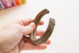 Antique African bronze cuff held in hand, showing its substantial form and aged patina.