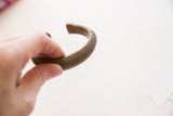 Angled profile of the antique bronze bracelet showing its cuff shape and surface patina.