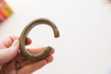 Antique African bronze cuff bracelet held to show its substantial form and scale.