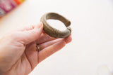 Antique African bronze bracelet held in hand to show its scale and ridged texture.