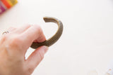 The sturdy, curved form and textured surface of an antique African bronze bracelet.