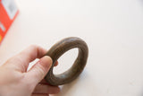 A hand holds the thick antique copper bracelet, illustrating its scale and aged surface.