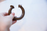 Antique African copper bracelet held in hand, showing its heavy form and aged patina.
