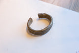 The aged patina and etched stripe design on an antique African bronze cuff bracelet.
