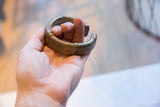 The weighty form of an antique striped bronze cuff bracelet held in hand.