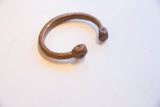 Open cuff design of an antique copper bracelet, showing the warm patina and faceted terminals.