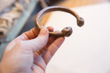 Etched details and form of an antique African snake cuff held in hand.