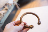 Antique copper alloy snake cuff held, showing its open form and etched details.