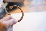 Aged copper alloy snake cuff bracelet held to display its open form.