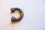 The solid, C-shaped form of a hand-worked antique African copper alloy bracelet.