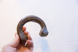 Hand-forged antique copper cuff held to show its substantial curve and scale.