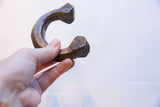 A hand holding the antique copper cuff, showing its substantial, faceted shape.
