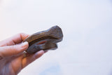 A hand holds the antique copper cuff, showing its etched geometric end.